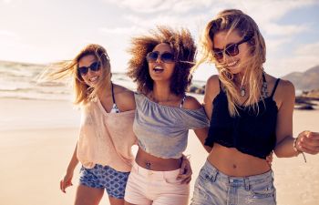 Three happy young women taking a walk along a beach.