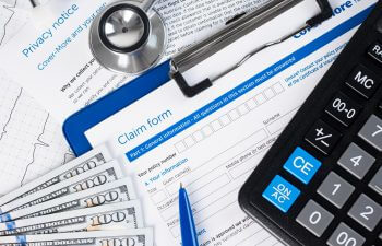 a stethoscope, money and insurance claim form