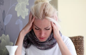 Stressed young woman with headache and sore throat.