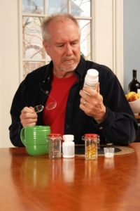 A senior men reading the label on the bottle with supplements.