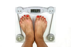 A woman on an electronic weighing scales that display HELP on the screen.