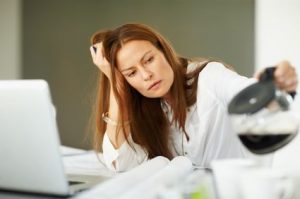 Fatigued woman at work getting a cup of coffee.