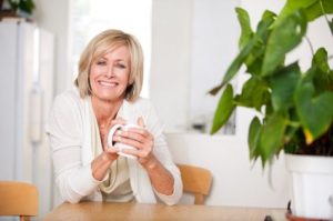 Happy mature woman enjoying a cup of coffee at comfort of her home.