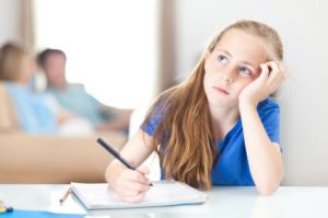 A schoolgirl daydreaming while doing her homework.